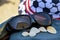 Summer vacation, beach holiday. Reflection of white beach umbrellas in sunglasses. Sunglasses and seashells on background of hat.