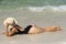 Summer vacation on beach. Woman in black swimwear lying on sandbeach. Girl enjoying sunbath near sea.
