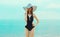 Summer vacation, beautiful young woman in bikini swimsuit and straw hat on the beach on sea coast background