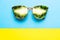 Summer vacation concept. Sunglasses with kiwi tropical fruits on blue yellow background