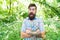 Summer vacation concept. United with environment. Man bearded hipster green trees background. Emotional nature lover