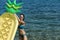 Summer vacation concept. Woman holds air mattress pineapple shaped with sea or ocean on background. Lady with air