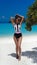 Summer vacation. Fashionable Woman in bikini suntanning on tropical beach. Slim girl posing on exotic island by beautiful