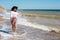 Summer vacation. Happy young boho woman walking in sea waves in sunny warm day at tropical island and blue sky. Space for text.