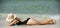 Summer vacation on sea. Girl sunbath near ocean. Woman in black swimwear lying on sand beach.