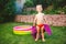 Summer vacation theme. A small 3 year old Caucasian boy playing in the backyard of a house on the grass near a round inflatable co