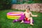 Summer vacation theme. A small 3 year old Caucasian boy playing in the backyard of a house on the grass near a round inflatable co