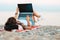 Summer vacation. A woman with a tattoo on her arm lies on the beach on the sand and works on a laptop. Rear view. The concept of