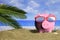 Summer vacations - Piggy bank on a sandy beach. 3d illustration