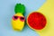 summer vibrant blue and yellow background with funny pineapple toy in sunglasses and squishy toy watermelon