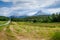 Summer view from below of Mount Heilhornet in Norway. High peaks rest on the blue sky. Green fields, forests and a road going to