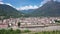 Summer view from drone of small town of Domodossola in Ossola valley surrounded by green Alps overlooking railway, Italy