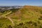 Summer view of Salisbury Crags from Arthur`s Seat in Holyrood Park with beautiful green grass and blue sky in Edinburgh, Scotland.