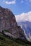 Summer view on a steep rocky slope of a mountain in a majestic gorge with white clouds in blue sky