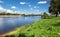 Summer view of the water surface and shores of the Volga river and the old Volga bridge in the background, city of Tver, Russia.