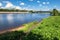 Summer view of the water surface and shores of the Volga river and the old Volga bridge in the background, city of Tver, Russia.