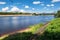 Summer view of the water surface and shores of the Volga river and the old Volga bridge in the background, city of Tver, Russia.