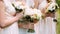 Summer wedding concept. Bridesmaids in ivory dresses holding wedding bouquets outdoor close up