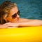 Summer woman lying on yellow floating mattress