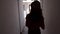 Summer woman silhouette walking in dark corridor. Walking girl inside hotel