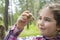 In the summer in the woods a little girl examines a snail