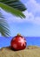 Summer xmas holidays concept. Christmas ball on sandy beach with palm tree, blue sea and sky background