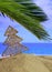 Summer xmas holidays concept. Christmas ornament on sandy beach with palm tree, blue sea and sky background