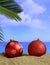 Summer xmas holidays concept. Christmas ornaments on sandy beach with palm tree, blue sea and sky background