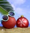 Summer xmas holidays concept. Christmas ornaments on sandy beach with palm tree, blue sea and sky background