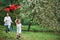 Summertime happiness. Positive female child and grandmother running with red and black colored kite in hands outdoors