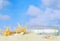 Summertime image of a beach scene on sand with a blue sky that has puffy white clouds in the distance.