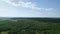 Summertime landscape with green trees and bright blue sky. Aerial view landscape with dense green forest and field