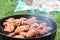 Summertime picnic in the courtyard - Cooking chicken wings on a round grill close up