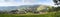 Summertime rural landscape banner, panorama - stacks of mown hay against the background of mountains Western Carpathians