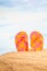 Summertime Season, colorful spotty sandals or flip-flop on the sandy beach with sunny colorful blue sky background and copy space.