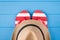Summertime vacation concept. Top above overhead view close-up photo of a pair of flipflops and a hat isolated on blue wooden