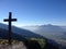 Summit cross on a high alpine mountain peak in Switzerland with a great view of the valleys and villages below and hazy mountains