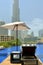 A sun bed and an umbrella next to swimmimg pool with a view on Burj Khalifa in Dubai Down Town