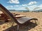 Sun beds on morning sandy beach with sun umbrellas and chair lounges background