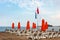 Sun beds and parasols in a row on a wooden platform in the sea.