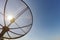 Sun behind satellite receiver with blue sky