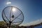 Sun behind satellite receiver with blue sky