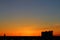 Sun below the horizon and television antenna in the background fiery dramatic orange sky at sunset or dawn backlit by