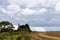 Sun breaking through clouds over lighthouse and wheat field