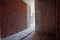 Sun bright light in dark narrow red brick wall corridor construction site of residential apartment building interior in