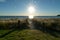 Sun bursts above horizon illuminating track across ocean to beach and track through dune.