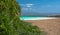 Sun canopy beach with azure sea and mountains in the background and green vegetation in the foreground