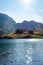 Sun casting rays on a mountain lake with mountain chalet and mountain  in the background and puffy clouds above