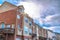 Sun and cloudy blue sky over three storey townhouses with attached garages