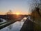 Sun comes up above Nieuwerkerk aan den IJssel in the Netherlands with ring canal and wooden bridge